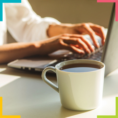 Mains d'une femme sur un clavier d'ordinateur avec un café